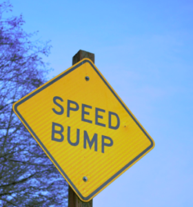 Yellow sign with the words "speed bump".
